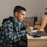 조지아주, 공립 대신 사립· 홈스쿨링 선택하면 6500달러 지원 Teenage boy doing homework using computer sitting by desk in room alone
